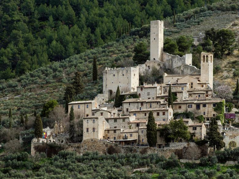 Immagine: Castle of Pissignano Alto, with medieval towers and stone houses nestled among olive groves and wooded hills 